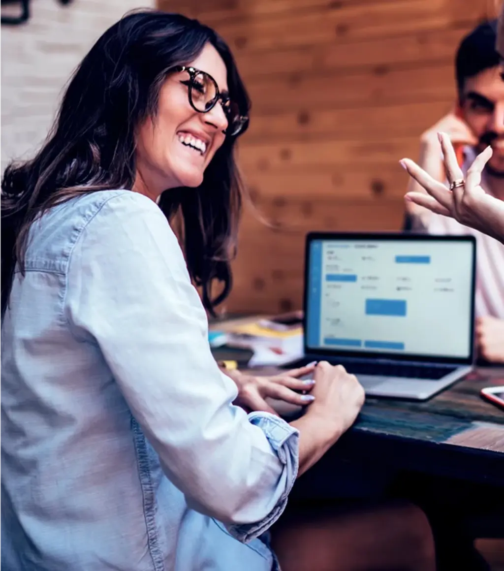 Smiling people and woman in front of laptop