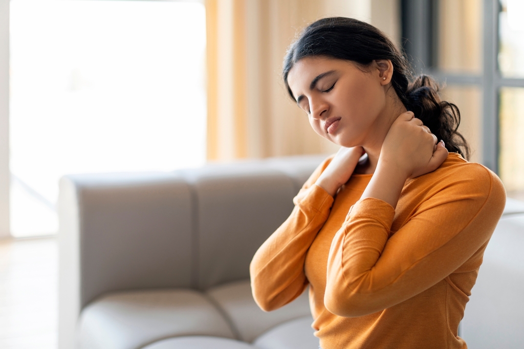 Frau mit Rückenschmerzen hält sich den unteren Rücken – sanfte chiropraktische Behandlung bei Move Chiropraktik in Frankfurt