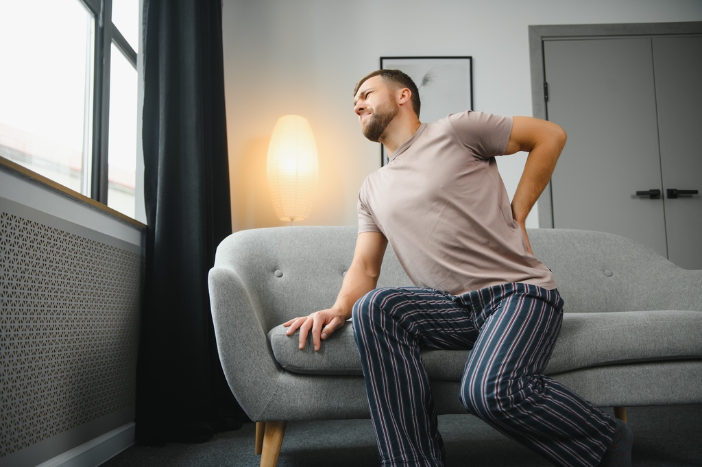 Frau mit Rückenschmerzen hält sich den unteren Rücken – sanfte chiropraktische Behandlung bei Move Chiropraktik in Frankfurt