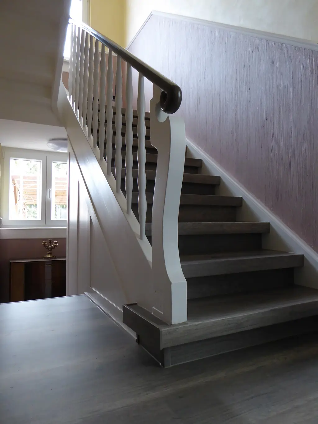 Renovierte offene Treppe mit Laminat in warmer Eichenoptik und weißem Stahlgeländer – Treppenrenovierung im Rhein-Main-Gebiet