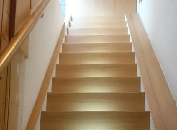 Renovierte offene Treppe mit Laminat in warmer Eichenoptik und weißem Stahlgeländer – Treppenrenovierung im Rhein-Main-Gebiet