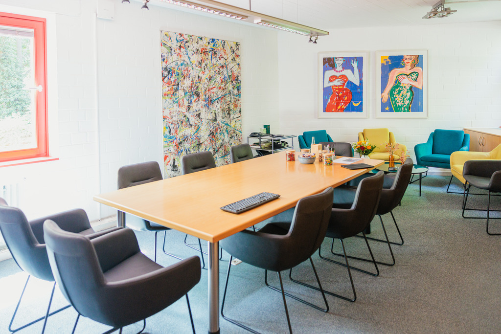 Besprechungsraum mit großem Tisch und bunten Stühlen