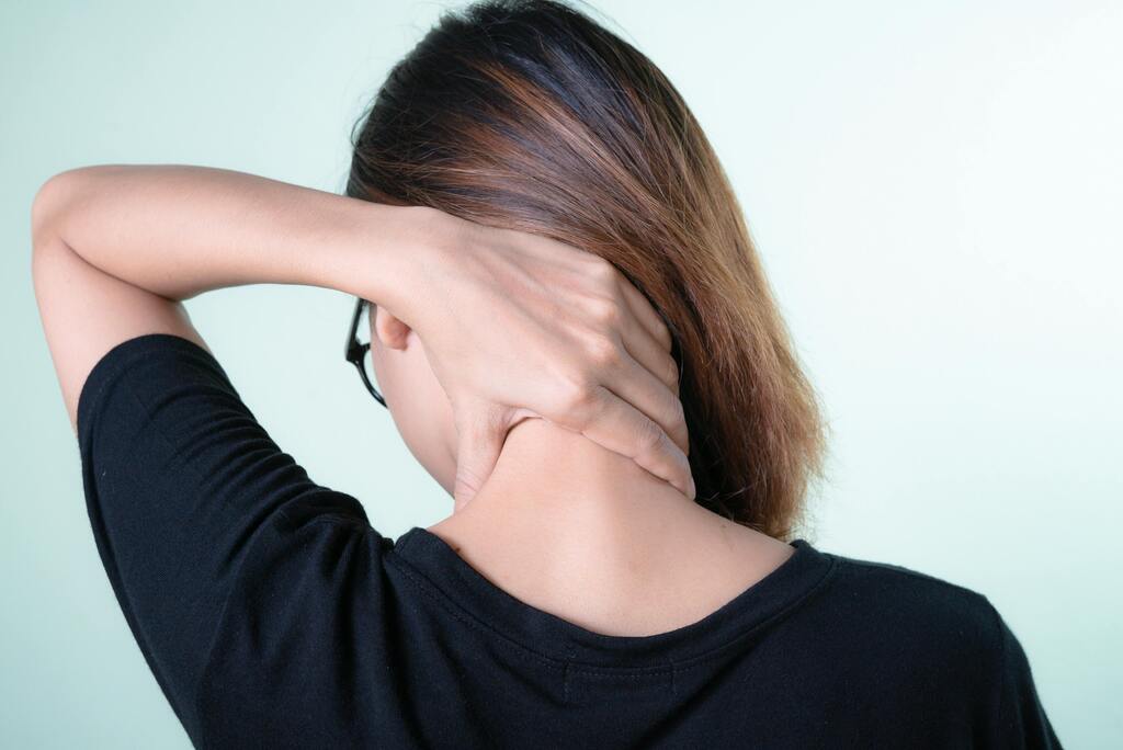 Frau mit Fibromyalgie berührt sanft ihren Nacken, Symbolbild für chronische Schmerzen