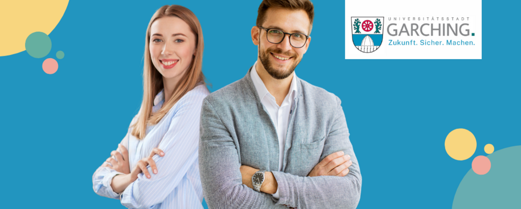 Zwei junge Fachkräfte stehen lächelnd vor dem Logo der Stadt Garching