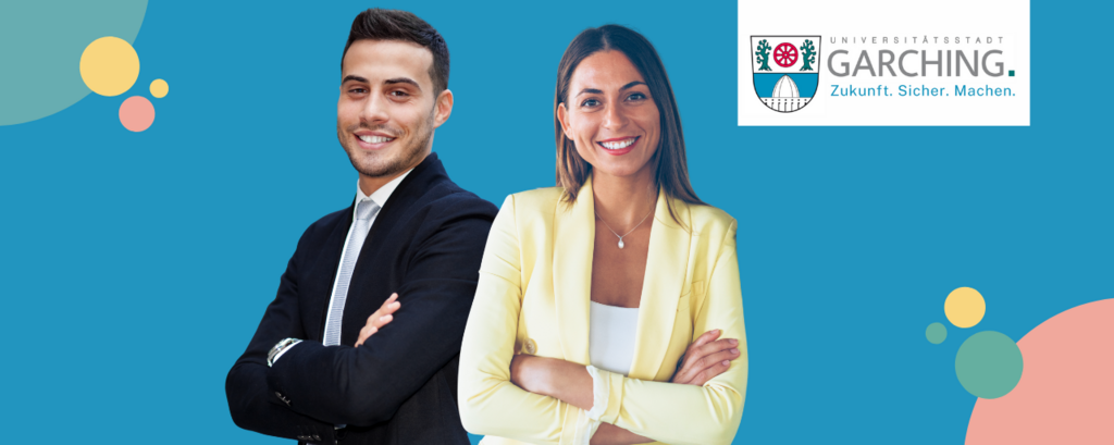 Zwei junge Fachkräfte stehen lächelnd vor dem Logo der Stadt Garching