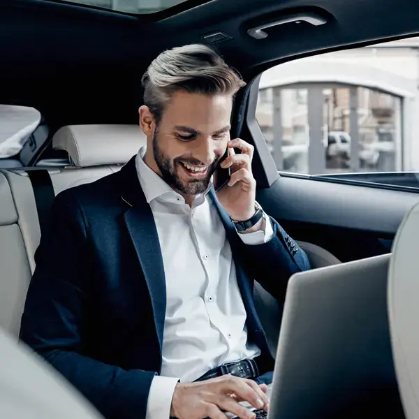 Foto von einem Mann, der in einer Limousine sitzt und am Laptop arbeitet