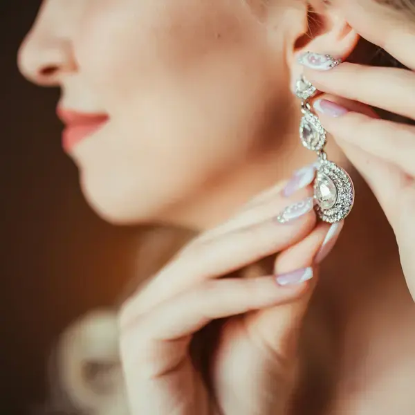 Foto einer jungen Frau, die ihre Brillantohrringe richtet