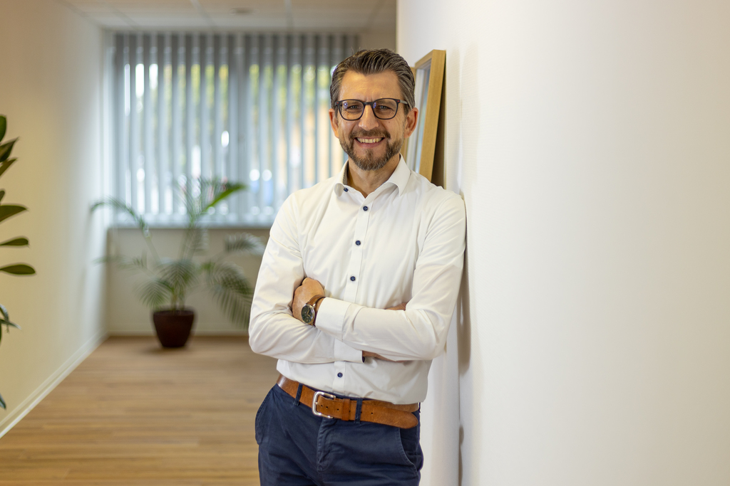 Dirk Kastner lehnt an einer weißen Wand in modernen Raum.