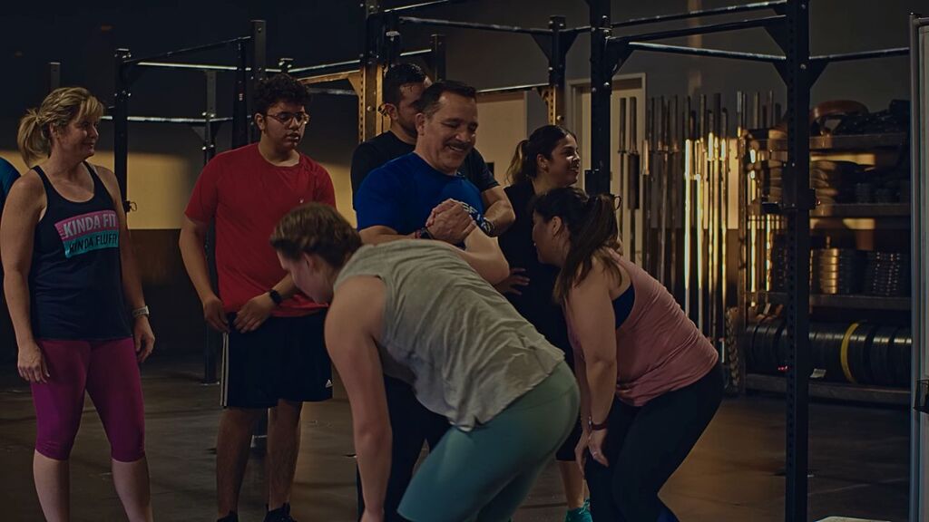 “CrossFit Rave coach supporting members during a group workout, highlighting community and encouragement.”