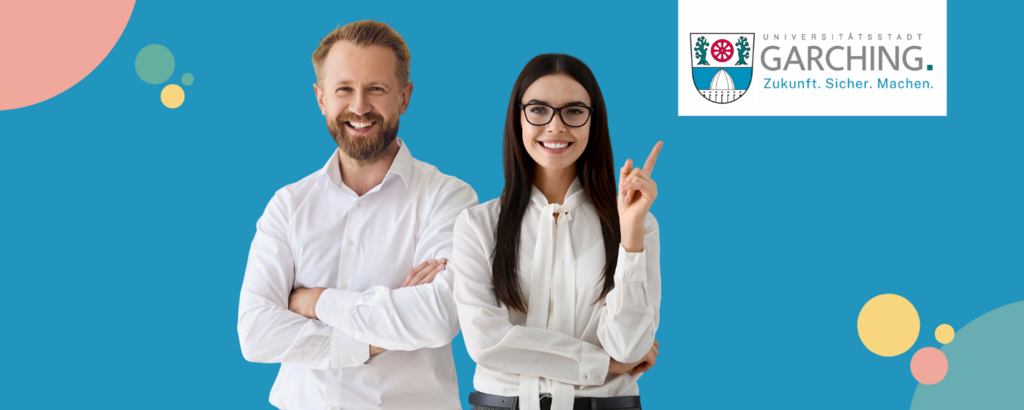 Zwei junge Fachkräfte stehen lächelnd vor dem Logo der Stadt Garching