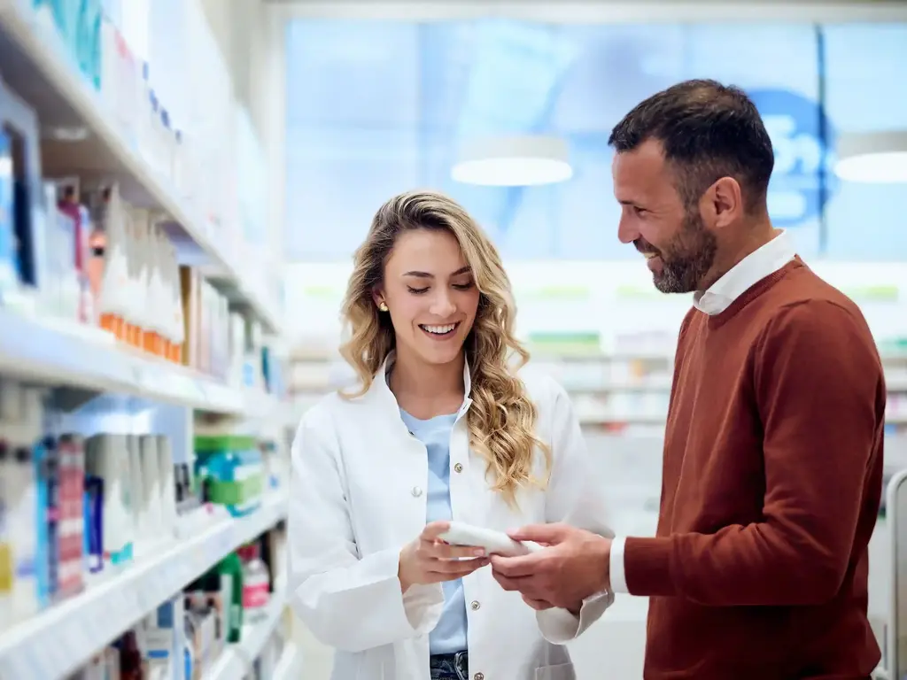 Mitarbeiterin Apotheke präsentiert Kunden Produkt