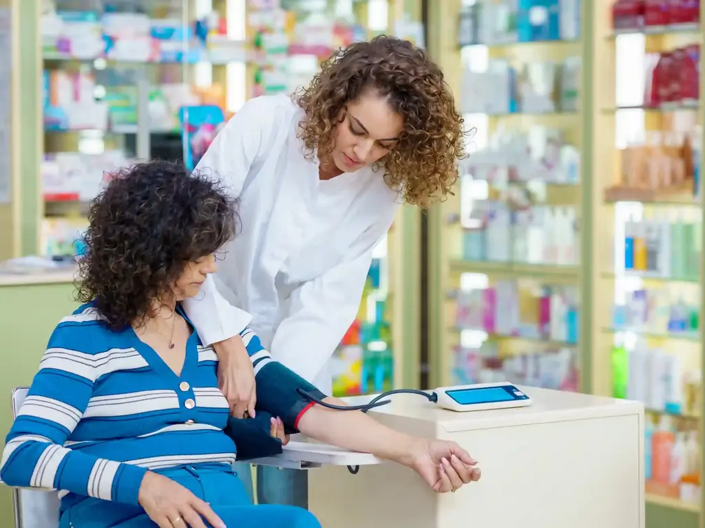 Apothekenmitarbeiterin vollzieht Blutdruckmessung