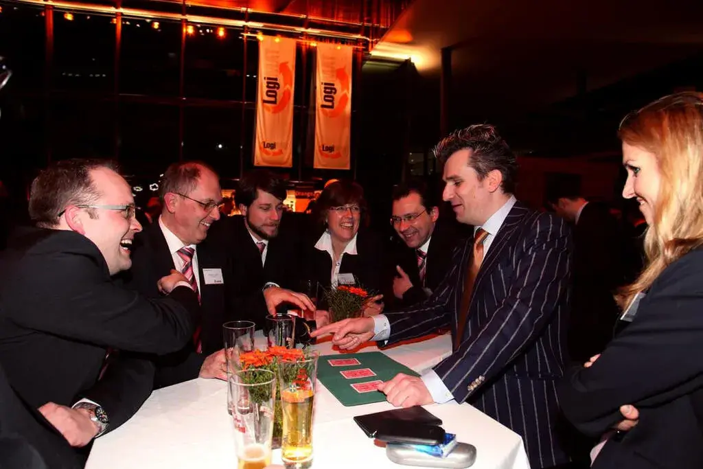 Lachende Gäste beim Zauberer-Act am Tisch bei einer Firmenveranstaltung