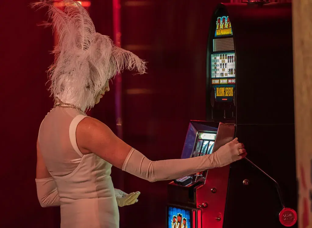 Showgirl in weißem Kostüm an einem Spielautomaten – Unterhaltung und Showacts für Casino-Events