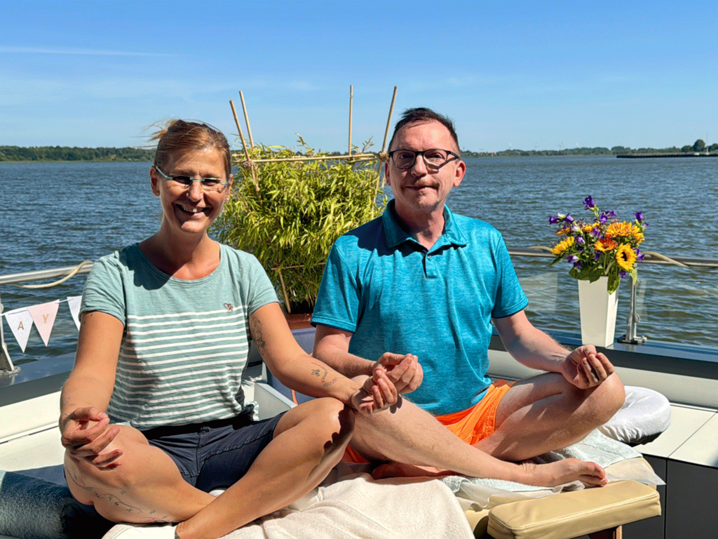 Entspannte Gäste auf der Terrasse der Wasservilla Coco de Mer mit Blick auf den Saaler Bodden an der Ostsee