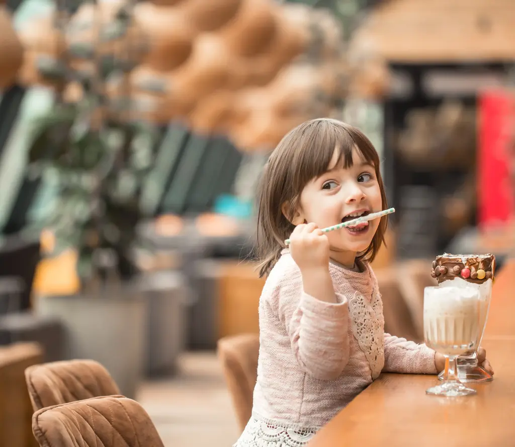 Kind leckt Strohhalm aus Milchshake ab