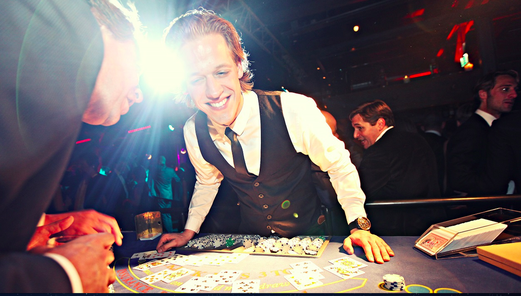 Begeisterter Croupier leitet eine Blackjack-Runde auf belebter Eventparty bei einem mobilen Casino-Event von Rent-A-Casino