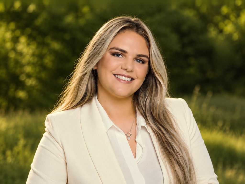 BrightWay Geschäftsführerin mit weißem Blazer lächelnd vor unscharfem Naturhintergrund