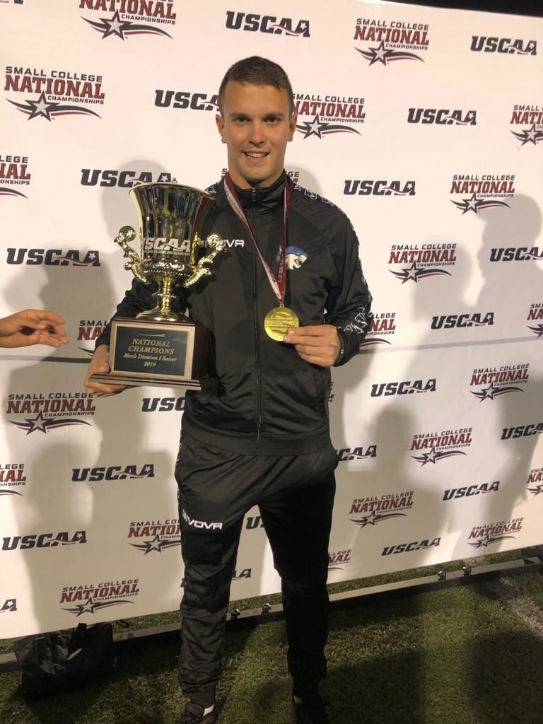 Soccer player Bogdan Milvanovic holding a trophy for a National Champion won with BSSCollege in Syracuse