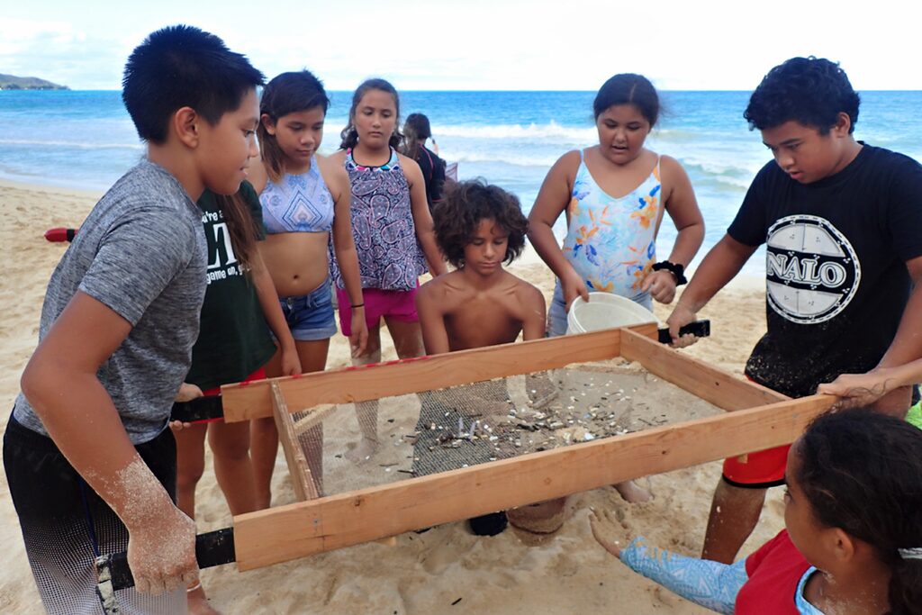kids ccleaning the beach of plastic in the sand