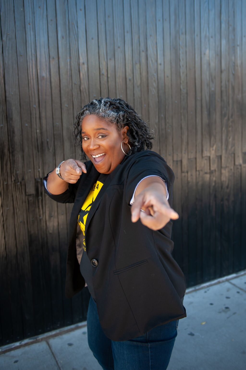 CEO Danielle "Dia" Winder laughing and pointing at the camera while wearing a blazer and jeans