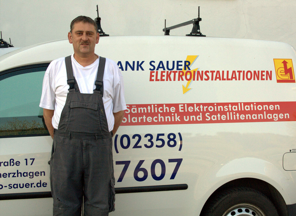 Frank Sauer steht vor einem Firmenwagen