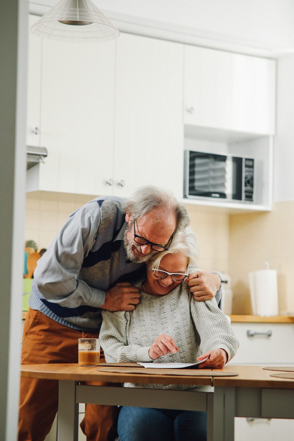 Older couple celebrating while reviewing paperwork at desk