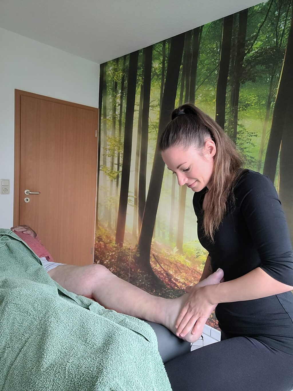 Ene Physiotherapeutin behandelt einen Patienten am Fuß