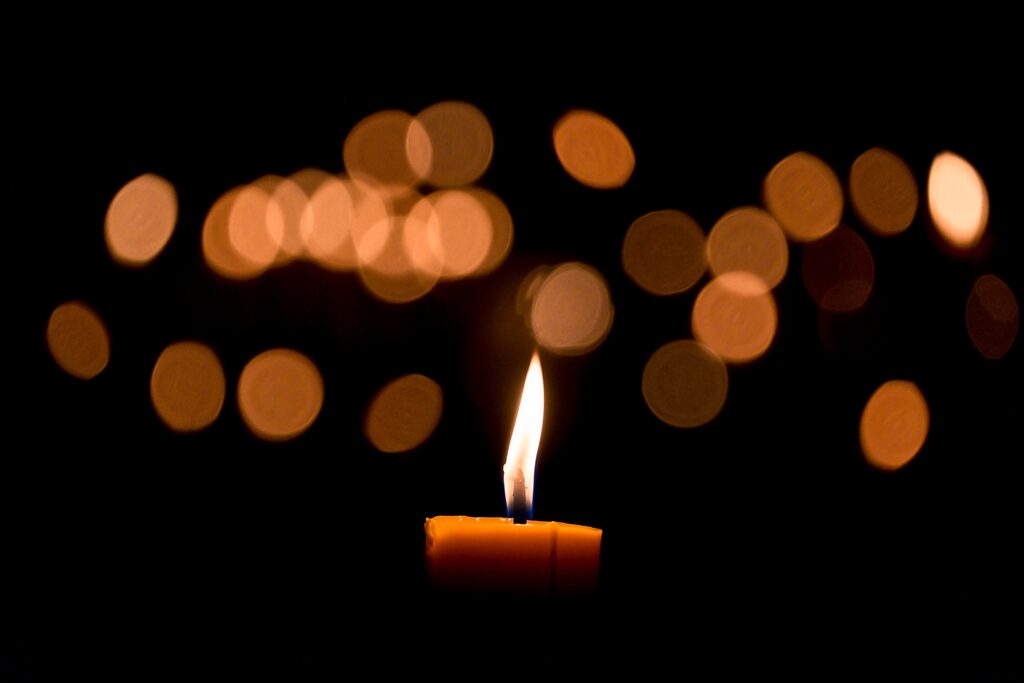 Eine Kerze wirf ein Lichterbild an die Wand.