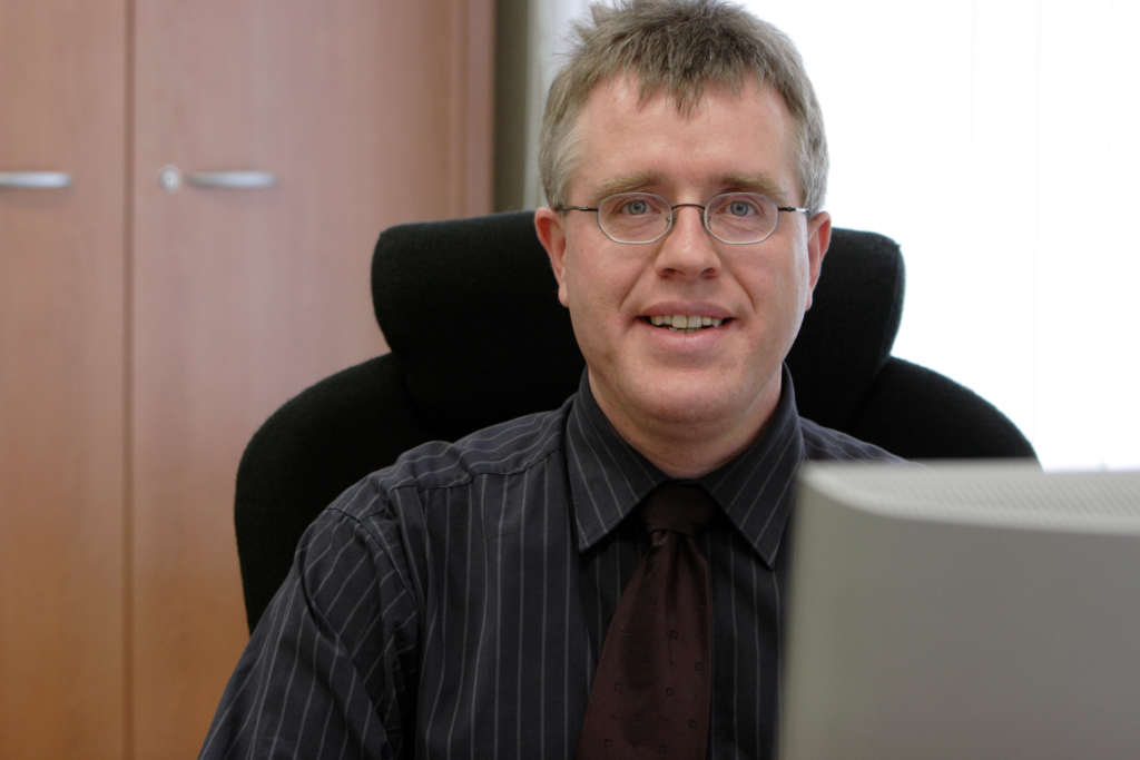 Herr Dr. Menne sitzt an seinem Schreibtisch