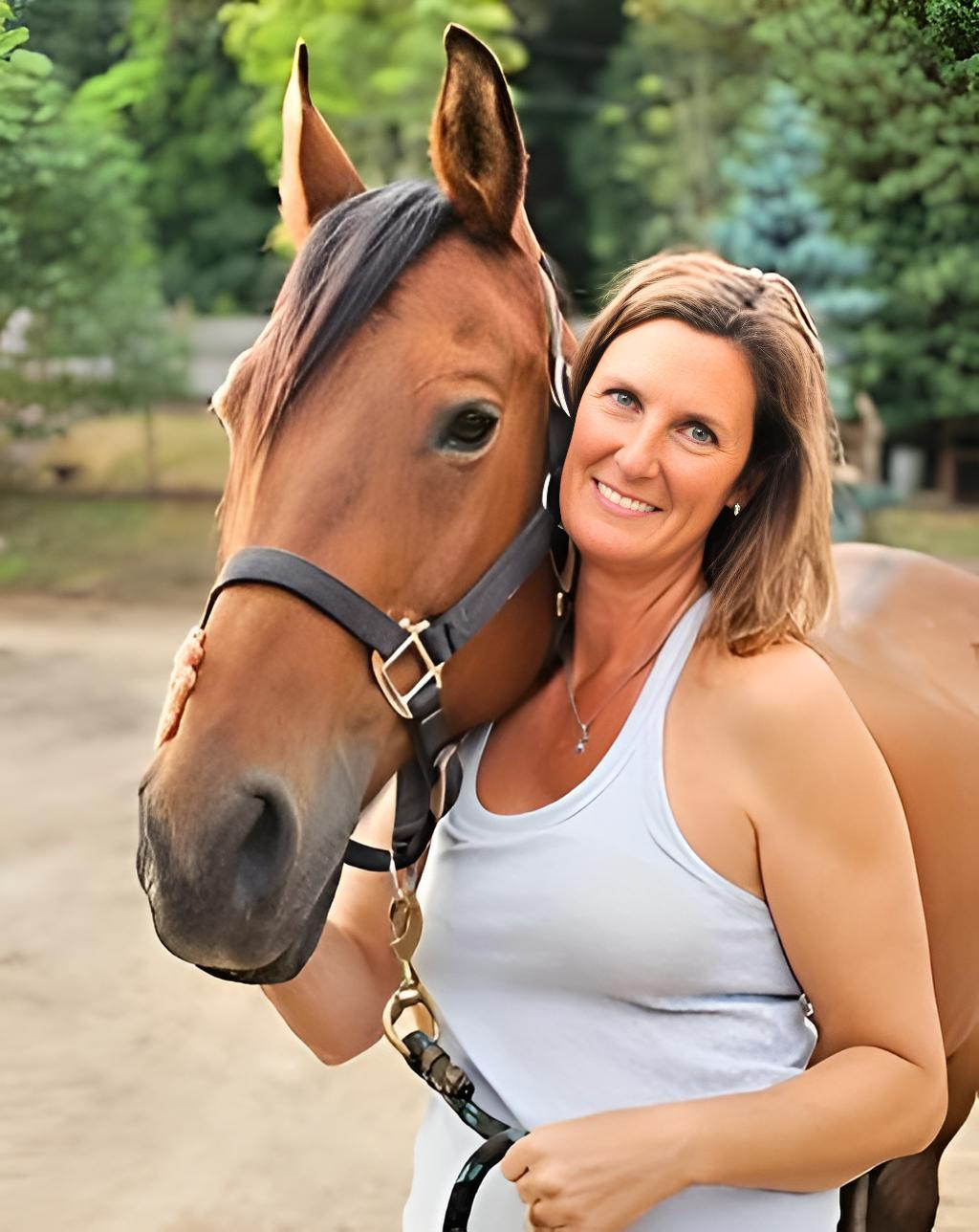 EFT Practitioner Penn Treado smiles at the camera, with her beautiful bay horse, Fancy, next to her in a leather head collar.