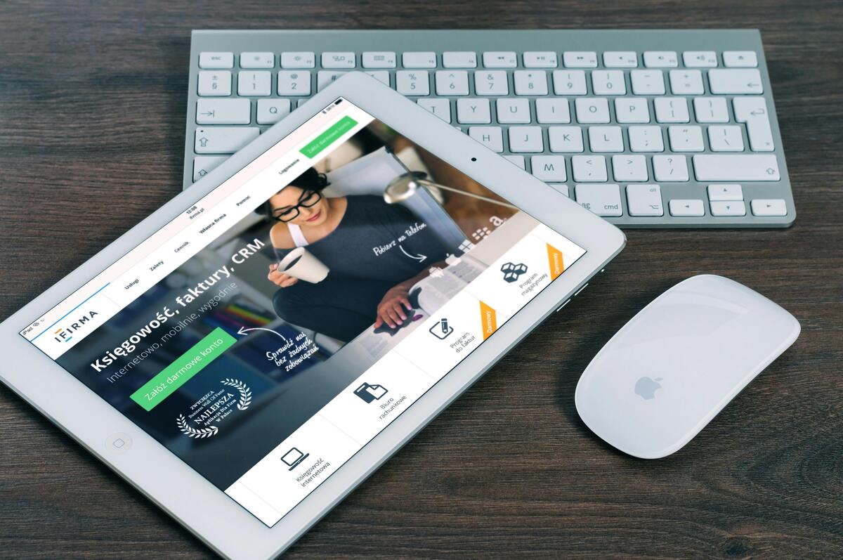 A tablet showing a financial website next to a white keyboard and mouse