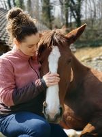 Isabelle lehnt Stirn an Pferd