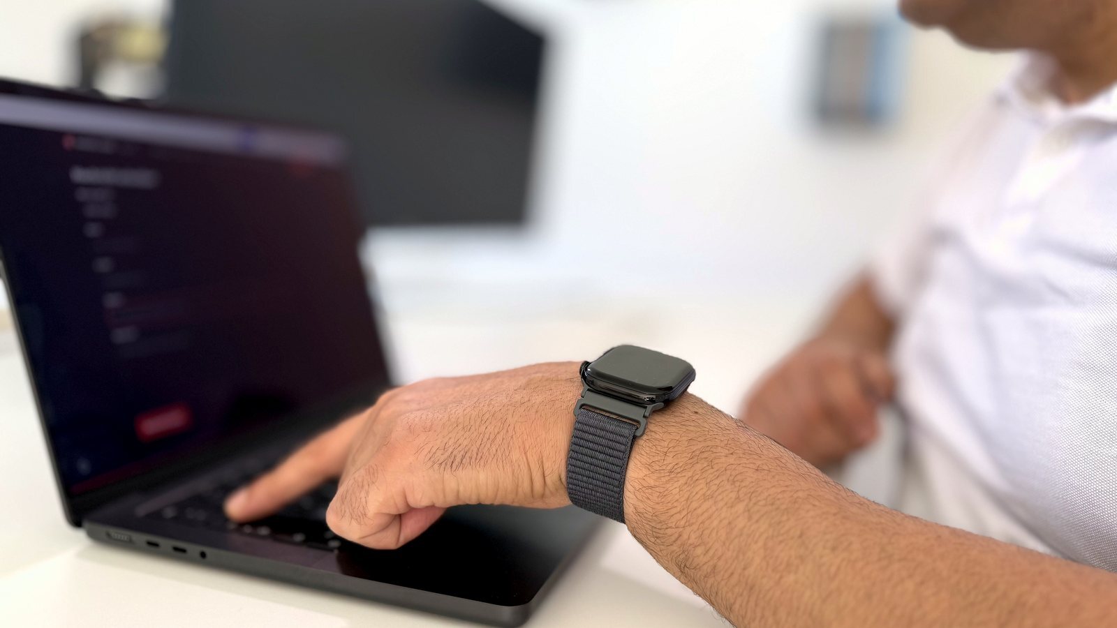 Arbeit an einer Website: die Hand auf der Laptop-Tastatur, im Hintergrund der Arbeitsplatz von hmaidan.media