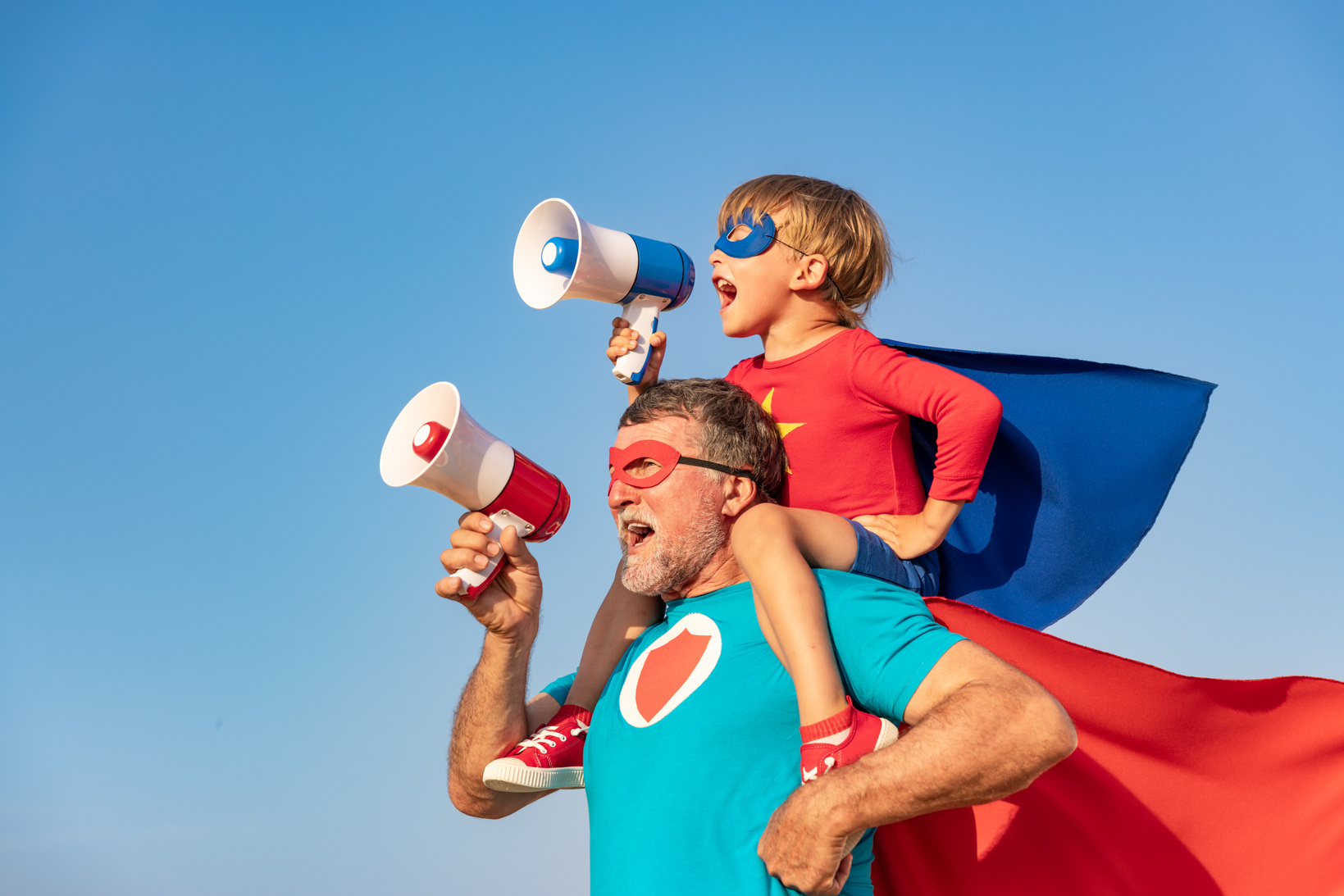 Kleiner Junge auf den Schultern seines Vaters spielen Superhelden