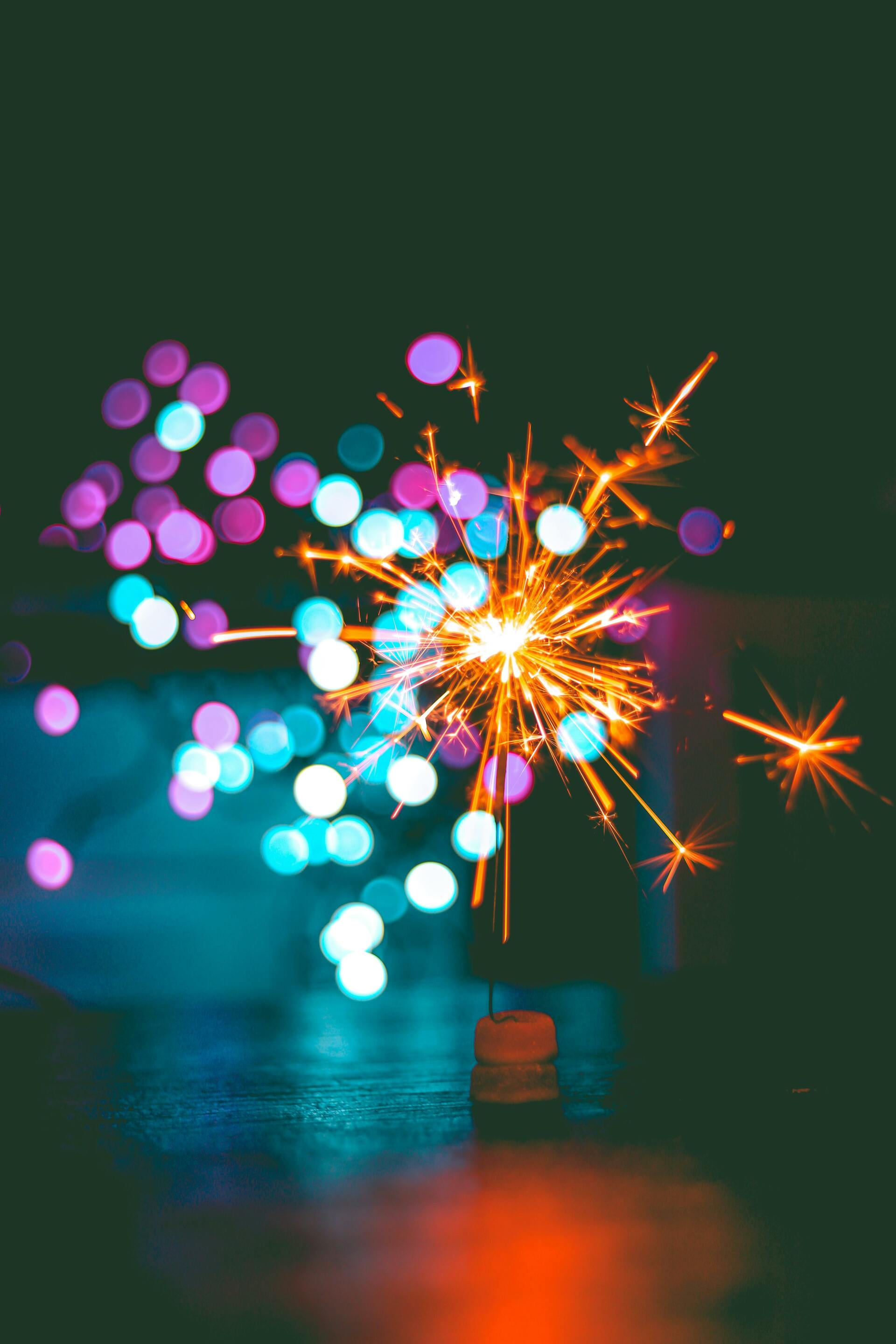 Funkelnde Wunderkerze vor farbigem Bokeh-Licht