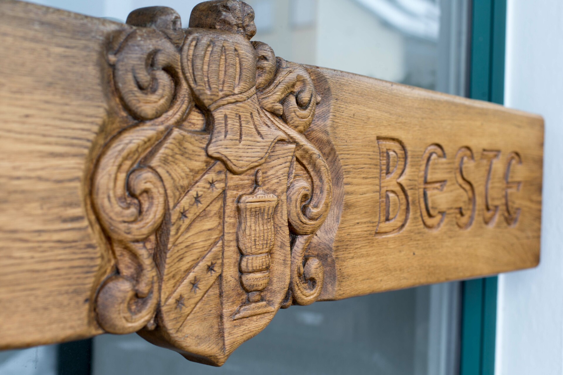 Zu sehen ist die Eingangstür mit dem Beste-Logo in Holz geschnitzt