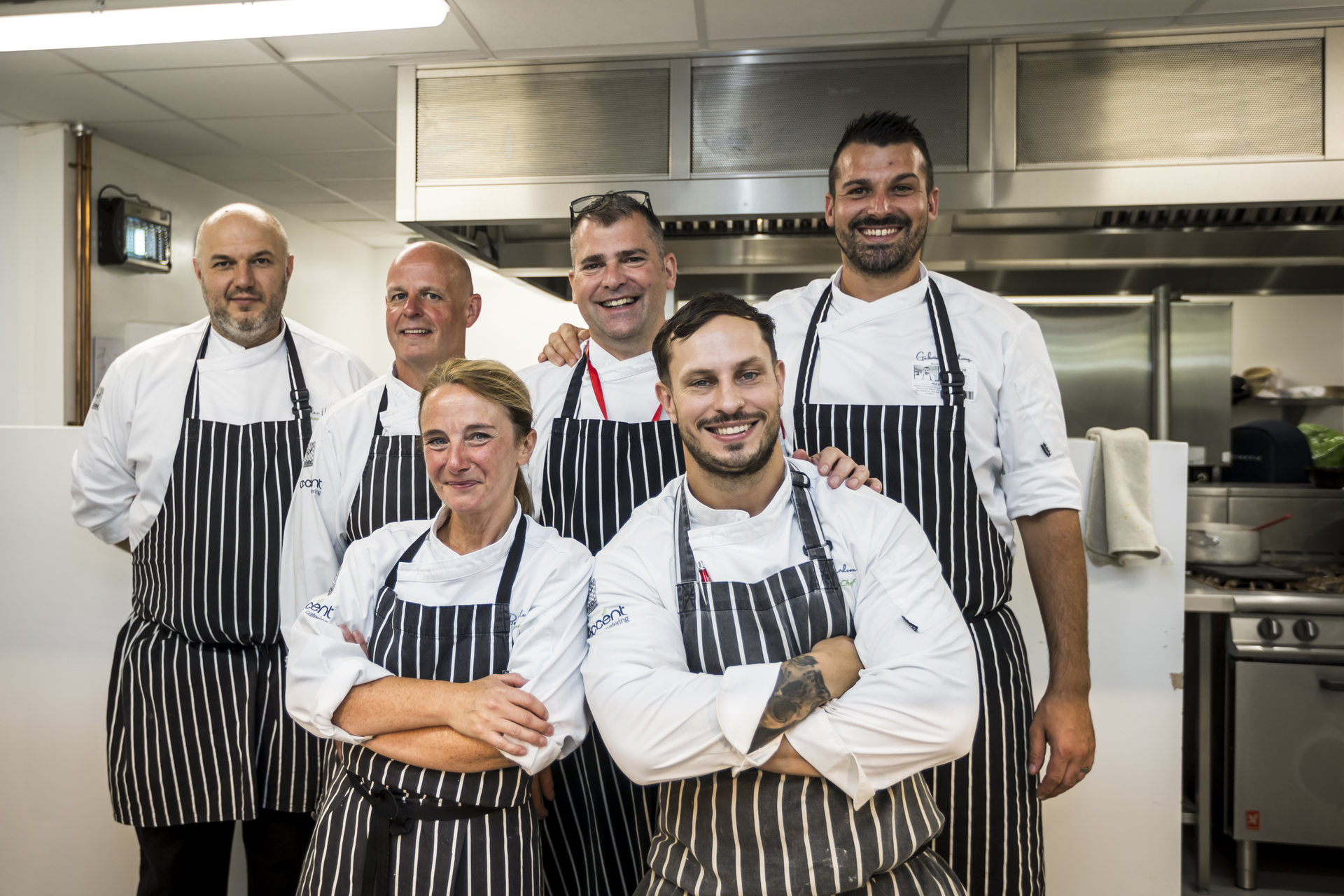 A team of people smiling in a kitchen.