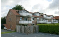 Mehrfamilienhaus mit Balkonen und rotem Satteldach