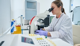 Eine Frau die eine Probe unter dem Mikroskop untersucht