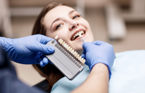 Eine Frau bei der nach einer passenden Zahnfarbe geschaut wird