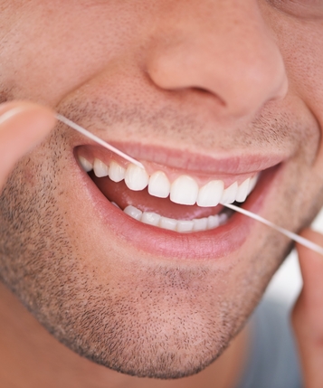 Ein Mann der seine Zähne mit Zahnseide reinigt