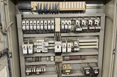Elektrischer Schaltschrank mit Relais, Sicherungen, Schaltern und Verdrahtung in mehreren Reihen.