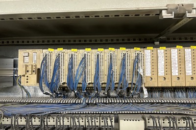 Reihe von Steuerungsmodulen mit blauen Kabeln in einem Schaltschrank.
