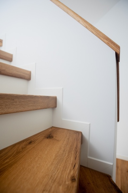 Renovierte offene Treppe mit Laminat in warmer Eichenoptik und weißem Stahlgeländer – Treppenrenovierung im Rhein-Main-Gebiet