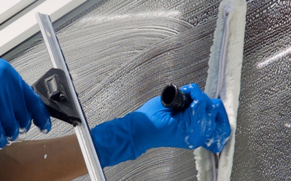 Fensterputzer reinigt Glas mit Abzieher