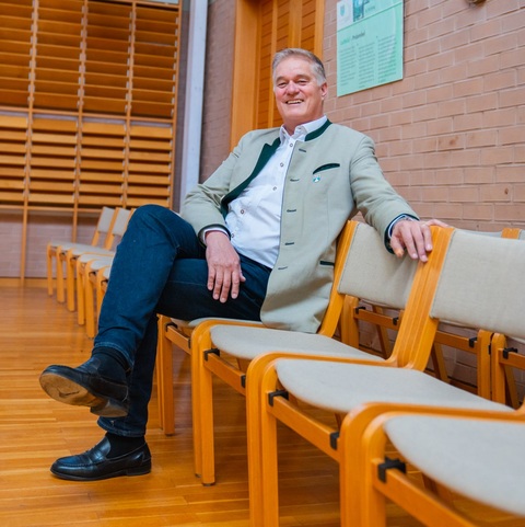 Sitzender Mitarbeiter – Ein Mitarbeiter sitzt entspannt in einem Stuhlkreis in einem Saal