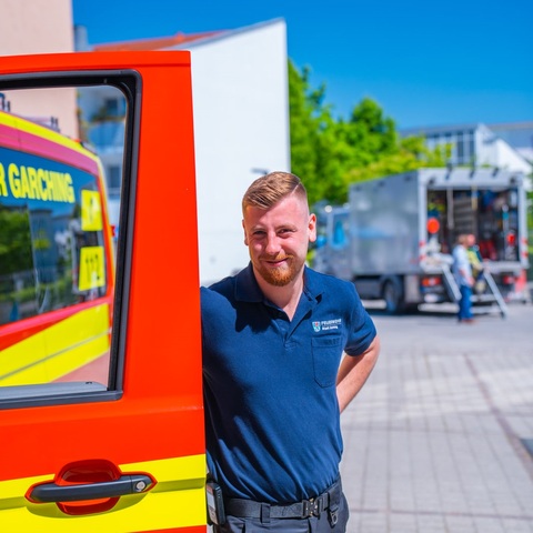 Feuerwehrmann am Fahrzeug – Feuerwehrmann steht an geöffneter Tür
