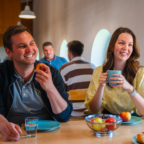 Pause im Aufenthaltsraum – Mitarbeitende unterhalten sich bei Kaffee, Obst und Gebäck