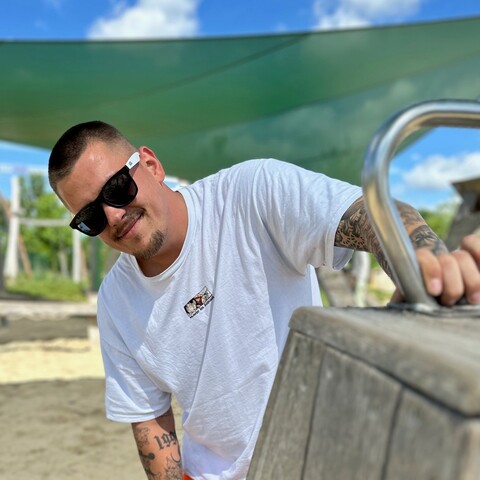 Mitarbeiter in weißem T-Shirt arbeitet auf einem Spielplatzgerät und lächelt